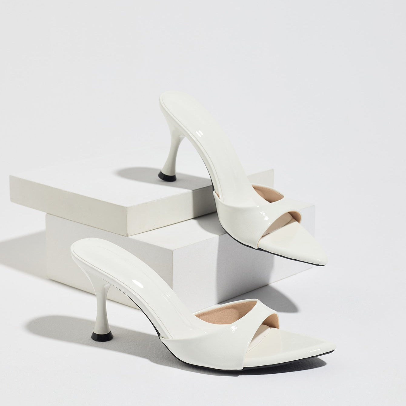 Mescini - White pointed toe mule heels as a pair on white risers, studio view, US sizes