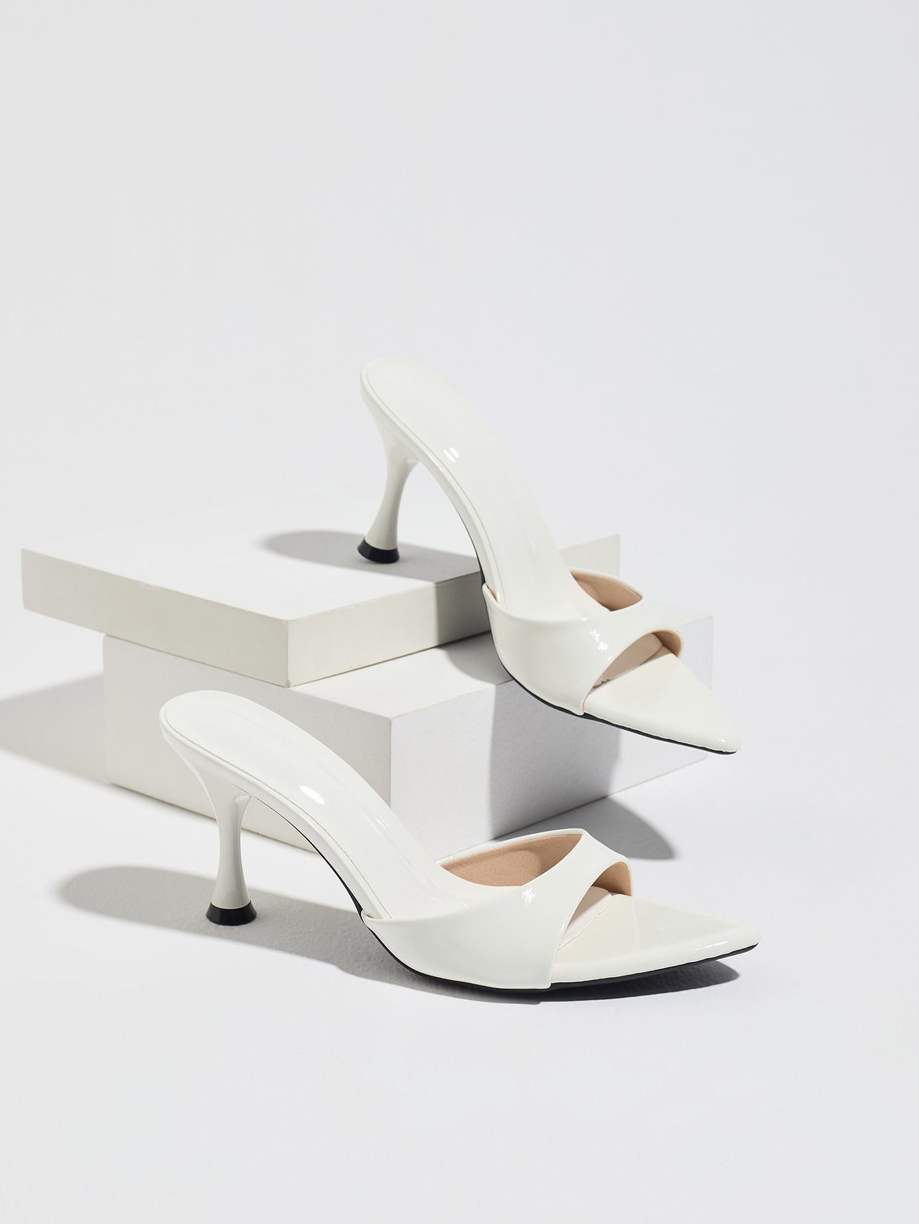 Mescini - White pointed toe mule heels as a pair on white risers, studio view, US sizes
