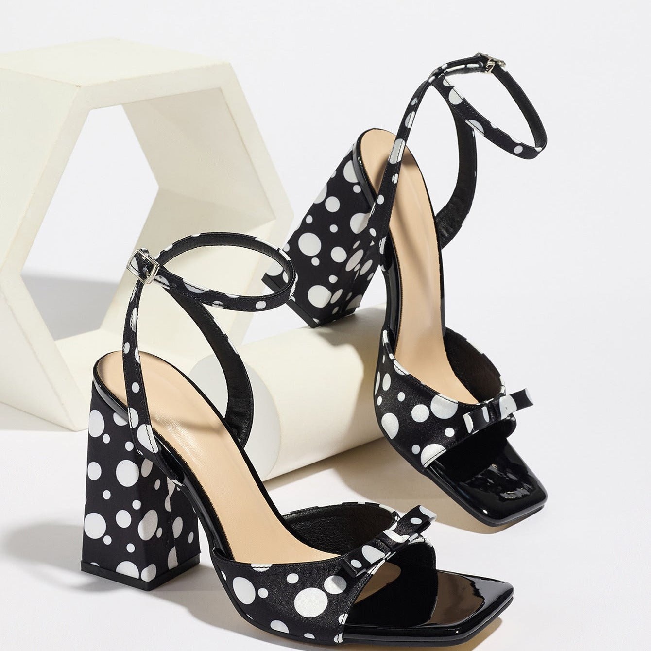 Mescini - Black polka dot block heel sandal pair beside a white riser, studio view, US