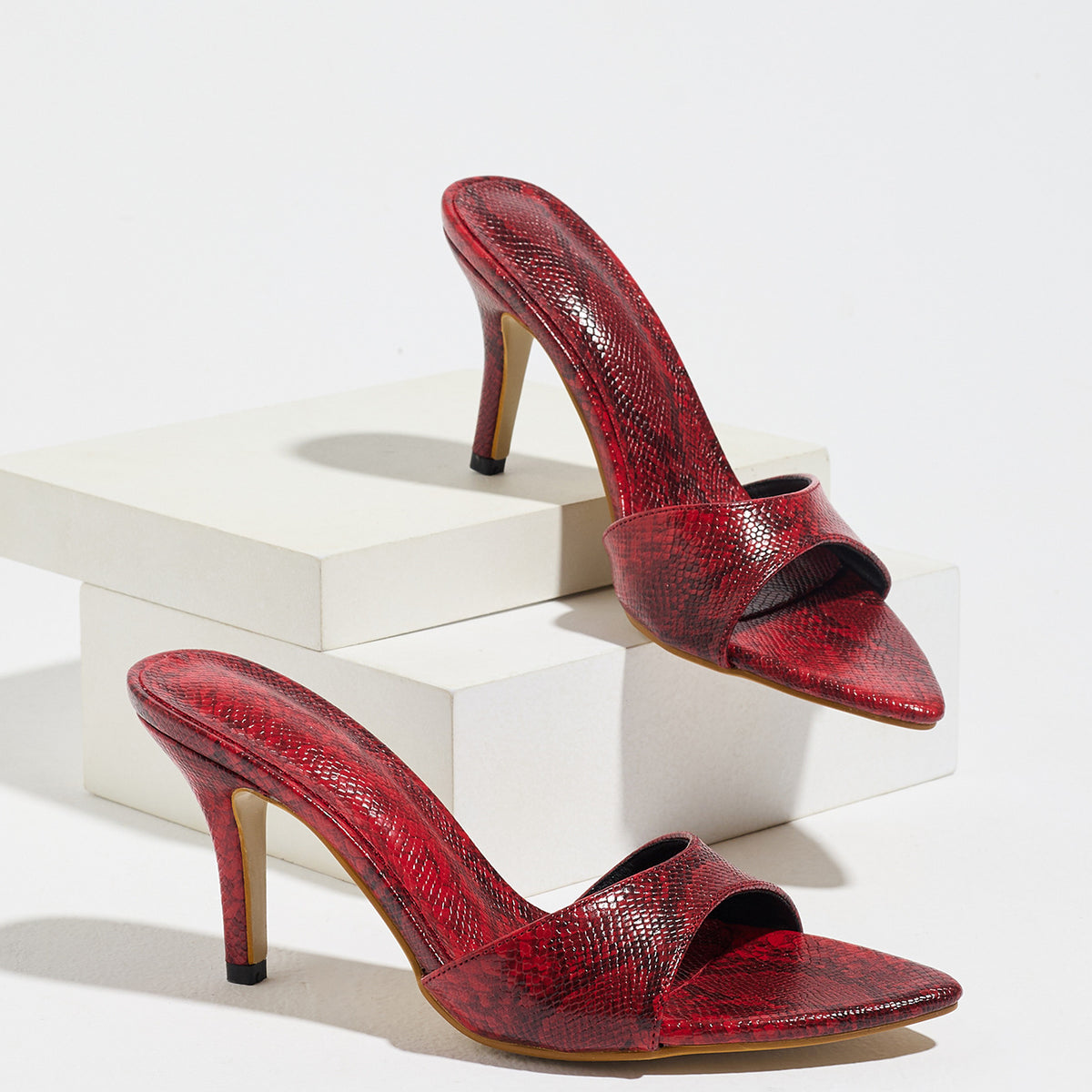 Mescini red snake print pointed toe mule heels, the pair displayed on white blocks, US women's sizes