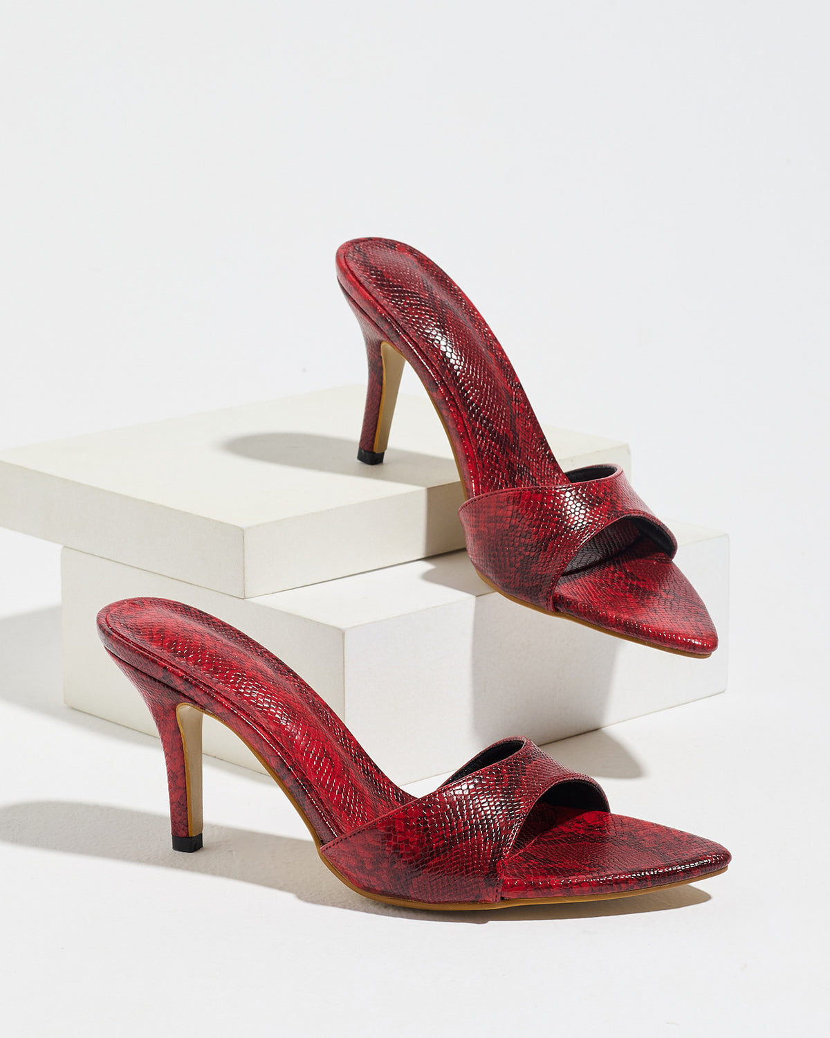 Mescini red snake print pointed toe mule heels, the pair displayed on white blocks, US women's sizes