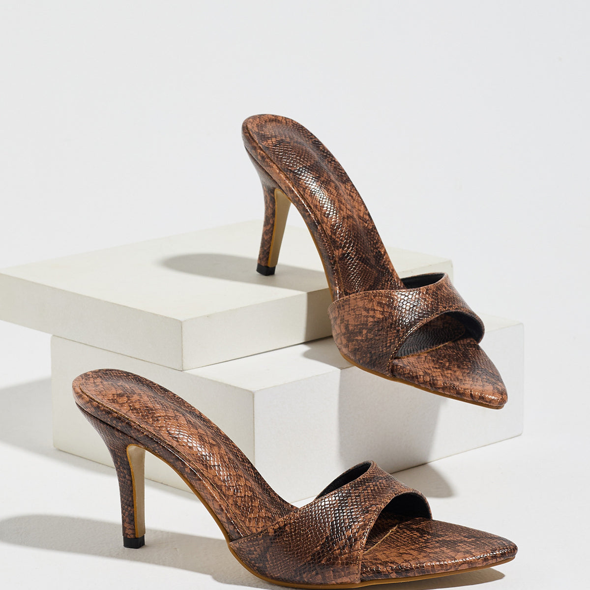 Mescini brown snake print pointed toe mule heels, the pair on white display blocks, US women's sizes