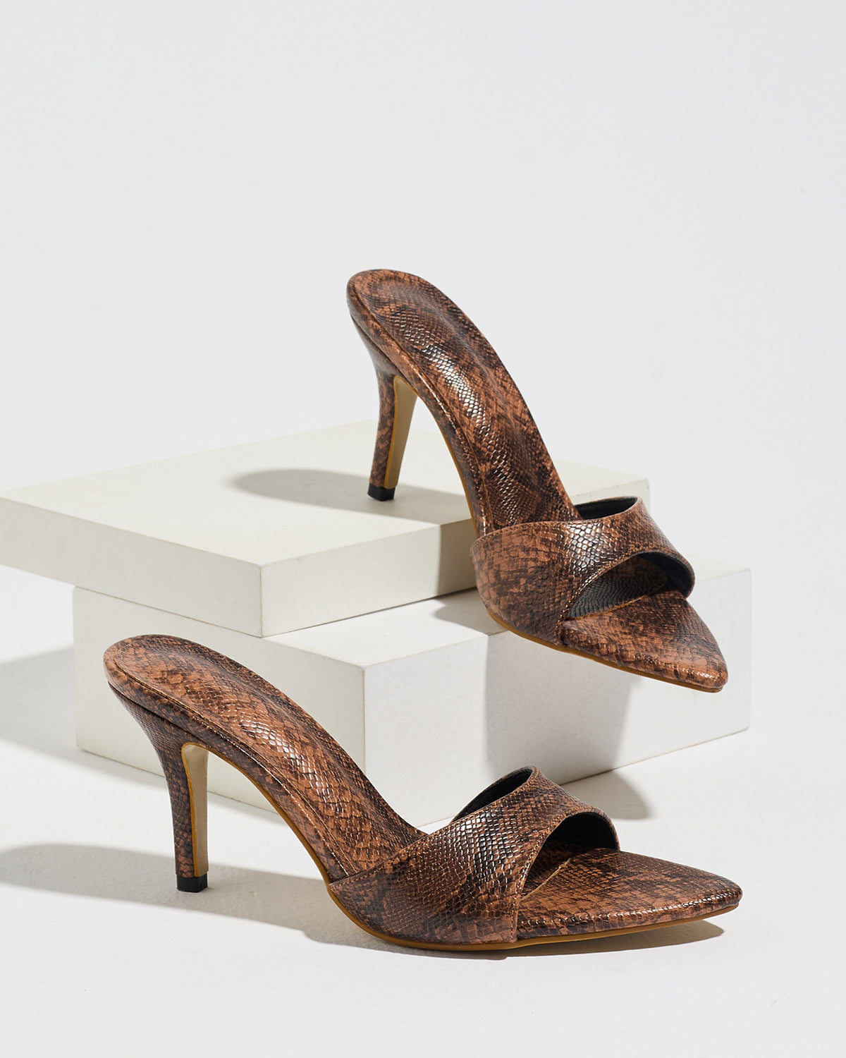 Mescini brown snake print pointed toe mule heels, the pair on white display blocks, US women's sizes