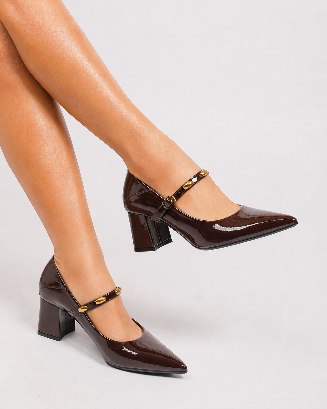 Mescini brown studded strap Mary Jane heels, worn with legs crossed and one foot raised, US women's sizes