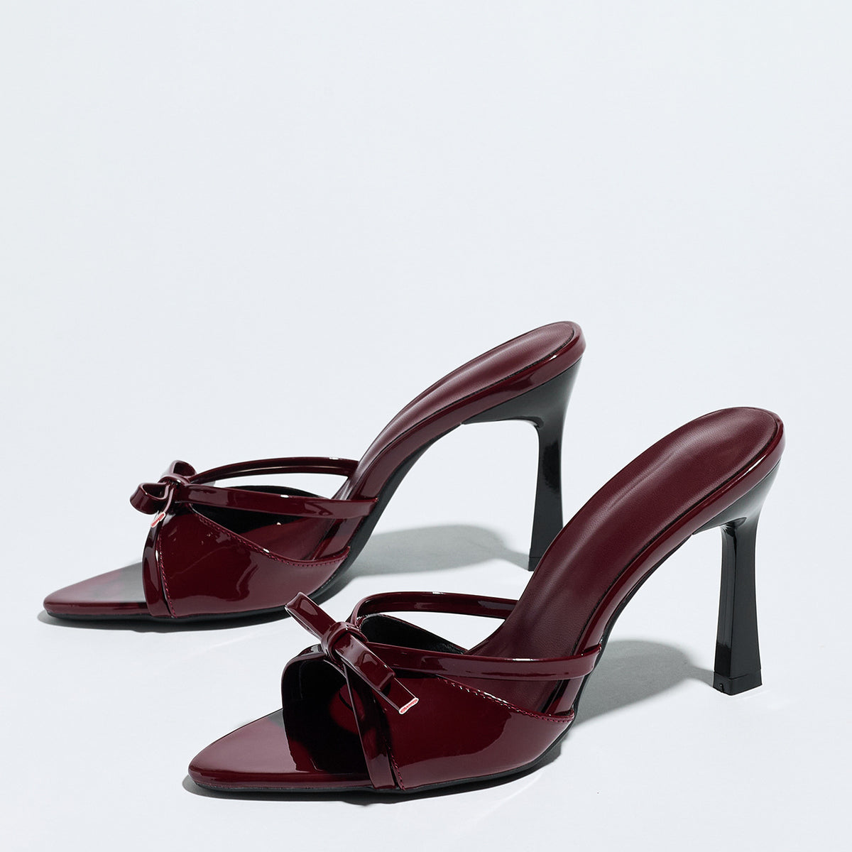 Mescini burgundy bow pointed toe stiletto mules, pair angled on a white backdrop, US women's sizes