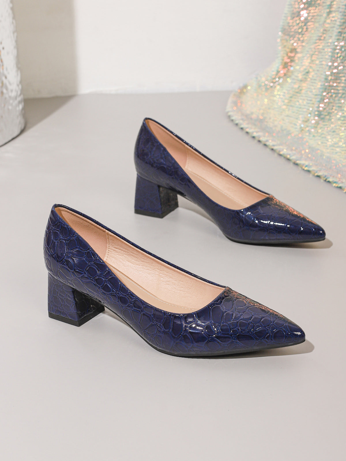 Mescini navy blue croc embossed block heel pumps, the pair set on a pale step, US women's sizes