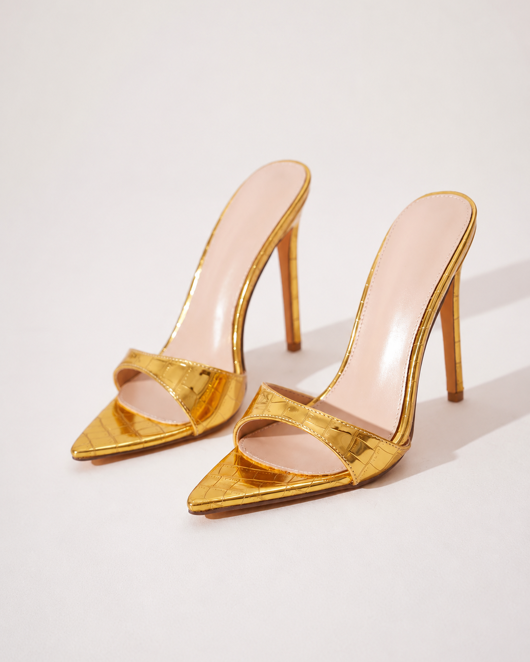 Mescini gold croc embossed pointed stiletto mules, the pair angled on a cream background, US women's sizes