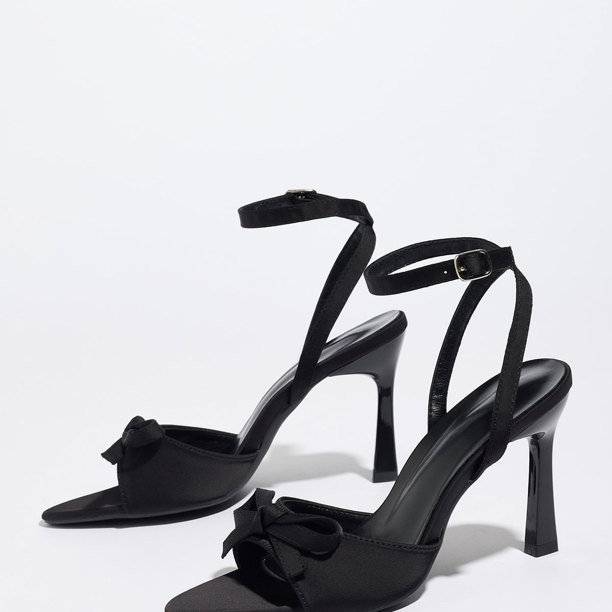 Mescini black satin bow ankle strap sandals, angled pair standing on a white surface, US women's sizes