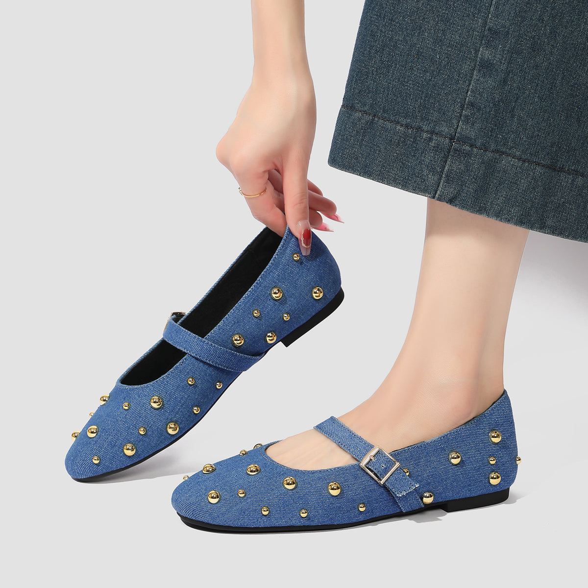 Mescini blue studded denim mary jane flats with a hand reaching down to them, US women's sizes