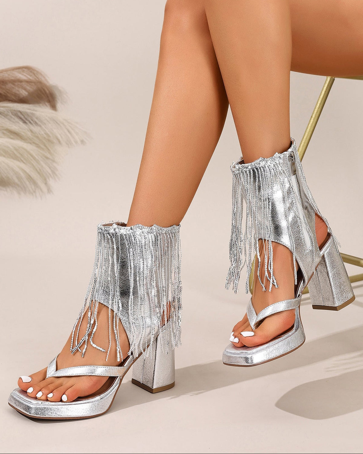 Mescini silver fringe thong chunky heel sandals, worn by a seated model against a pale wall, US women's sizes