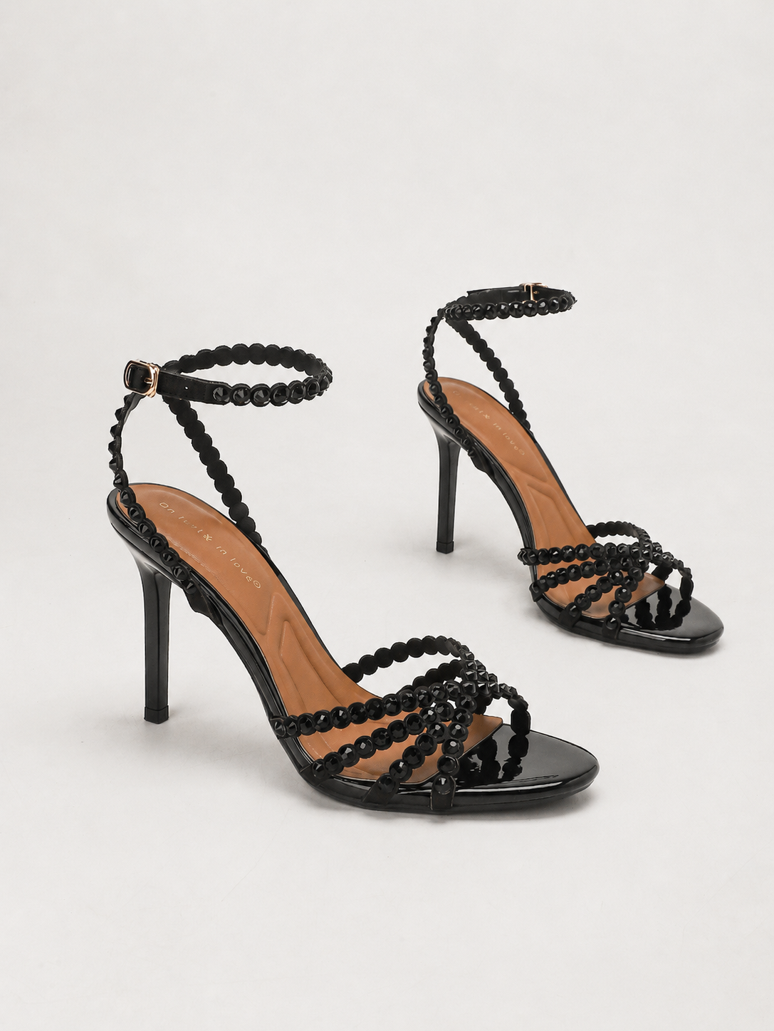 Mescini black rhinestone strappy stiletto sandals, pair set together on cream, US women's sizes