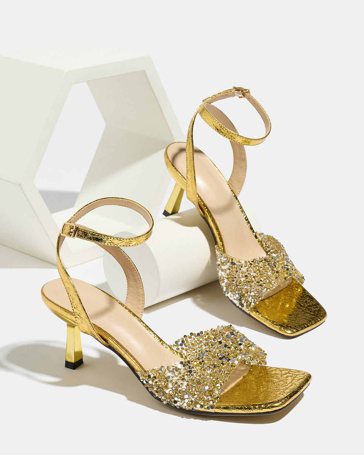 Mescini gold rhinestone square toe heeled sandals, pair styled on a white display prop, US women's sizes