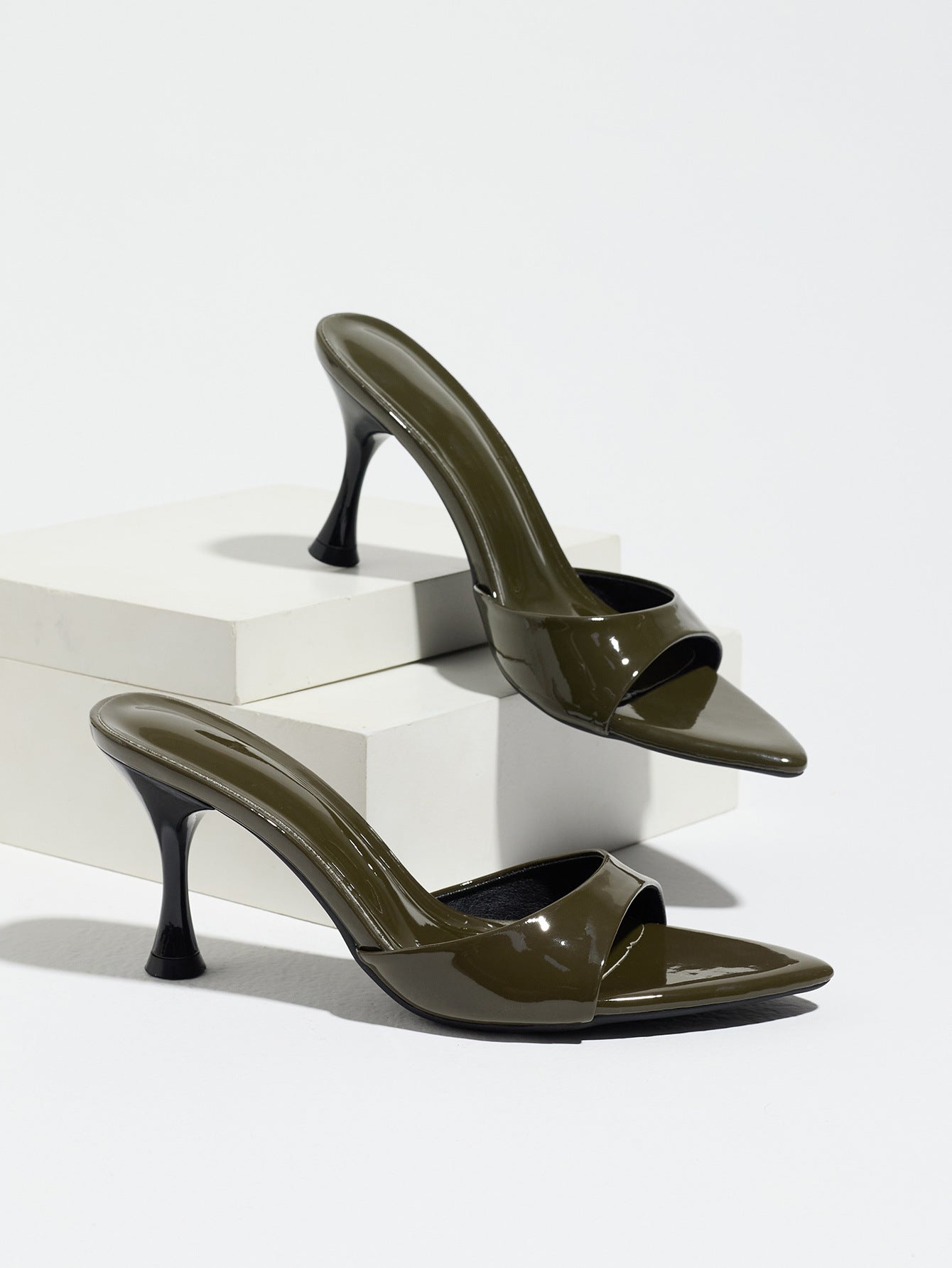 Mescini - Olive pointed toe mule heels as a pair on white risers, studio view, US sizes