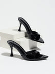 Mescini - Black pointed toe mule heels as a pair on white risers, studio view, US sizes