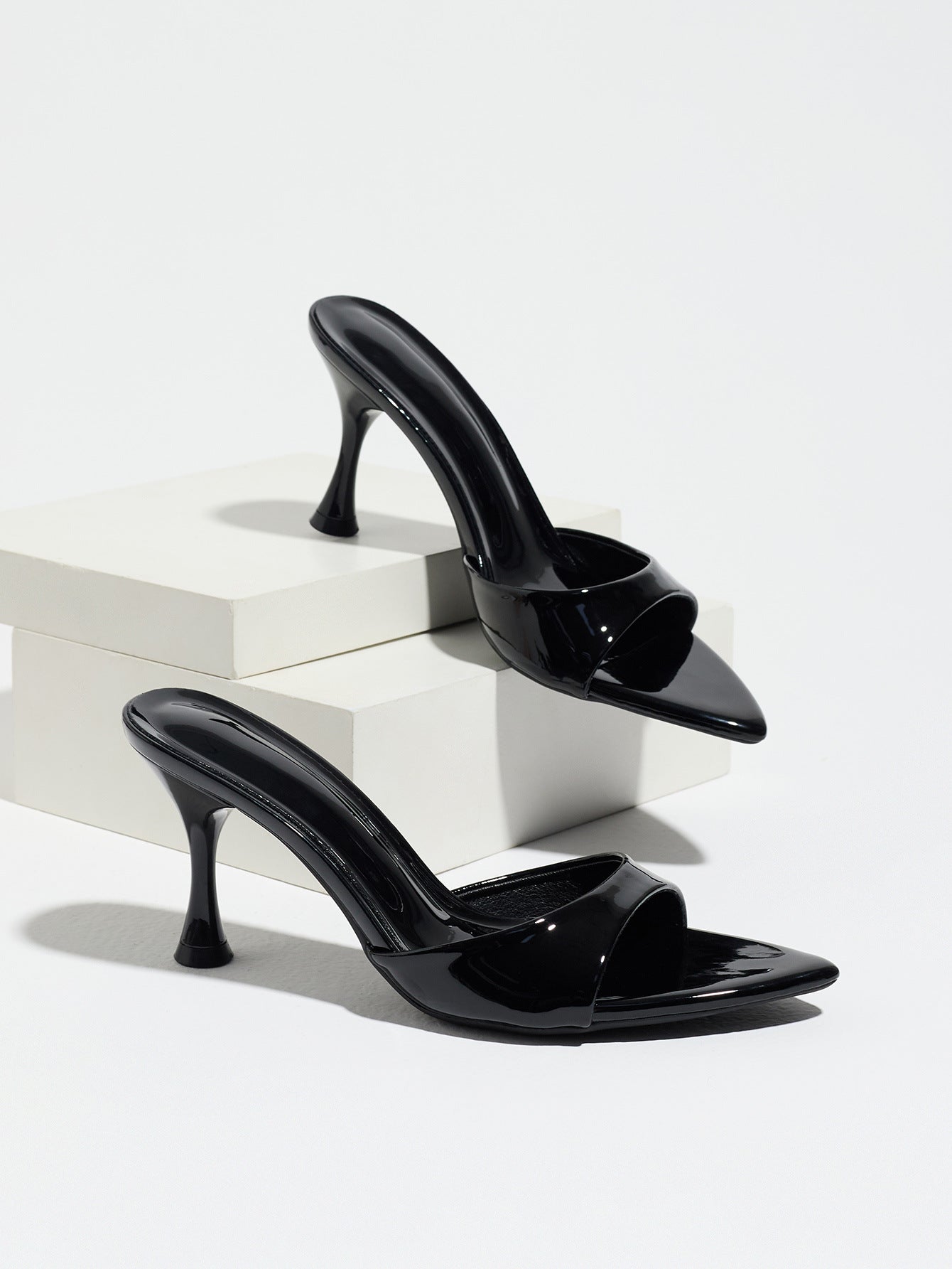 Mescini - Black pointed toe mule heels as a pair on white risers, studio view, US sizes