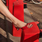 Mescini - Red bow detail mule worn against a red bench, three quarter street view, US
