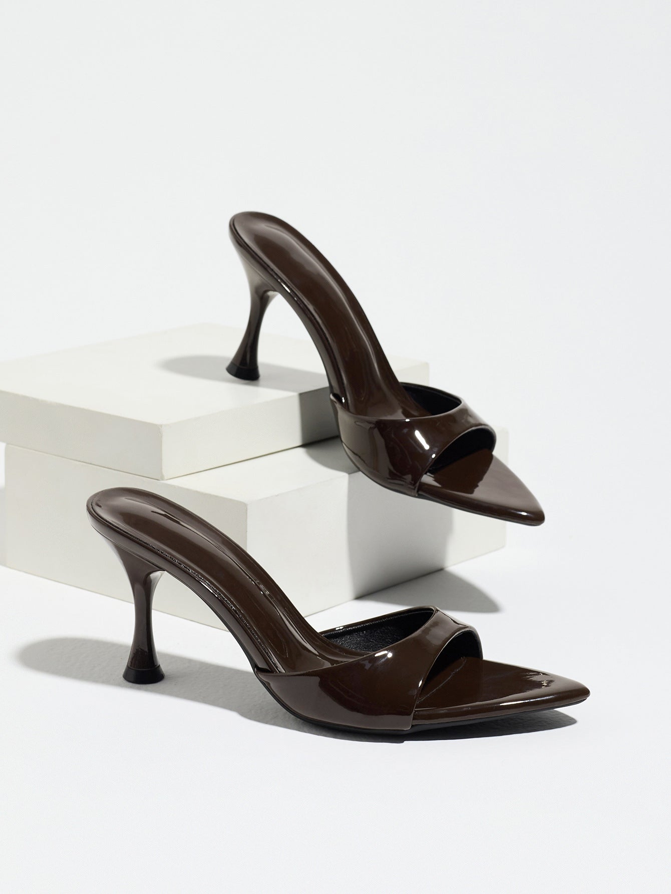 Mescini - Mocha pointed toe mule heels as a pair on white risers, studio view, US sizes