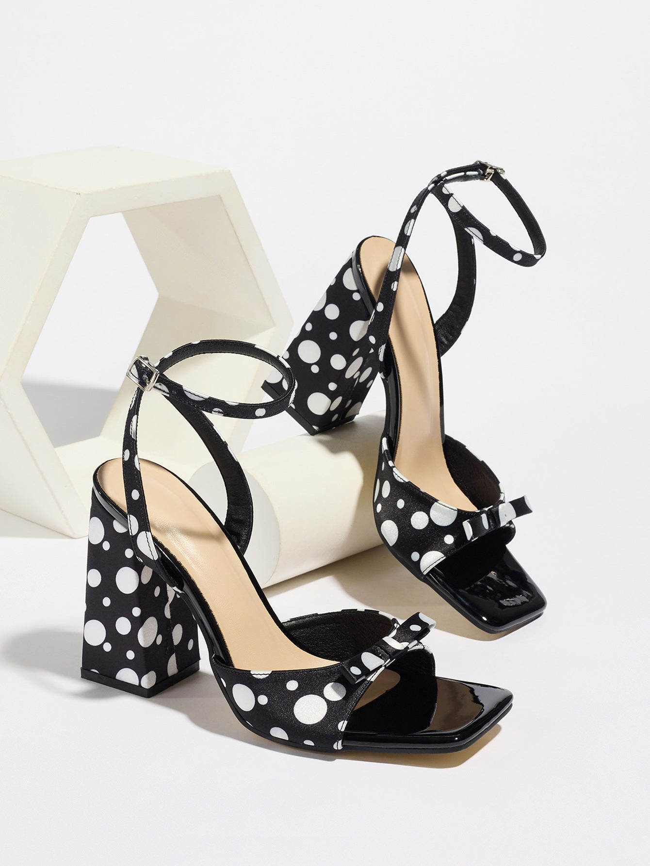 Mescini - Black polka dot block heel sandal pair beside a white riser, studio view, US