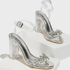 Mescini - Rhinestone clear sandals pair styled on a white block, angled product view, US sizes