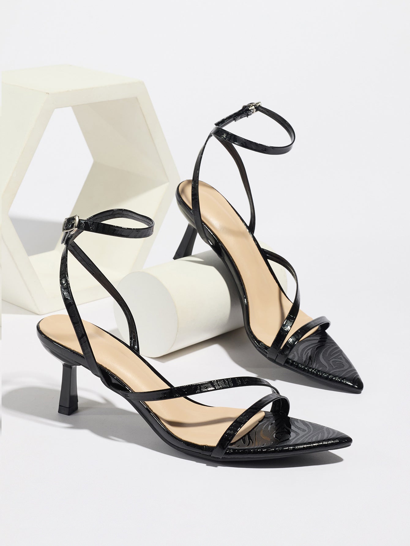 Mescini black strappy heeled sandals, pair propped on white display blocks, US women's sizes