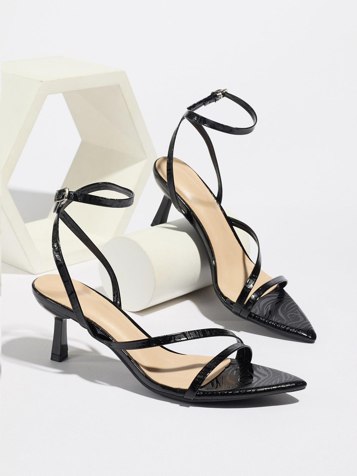 Mescini black strappy heeled sandals, pair propped on white display blocks, US women's sizes