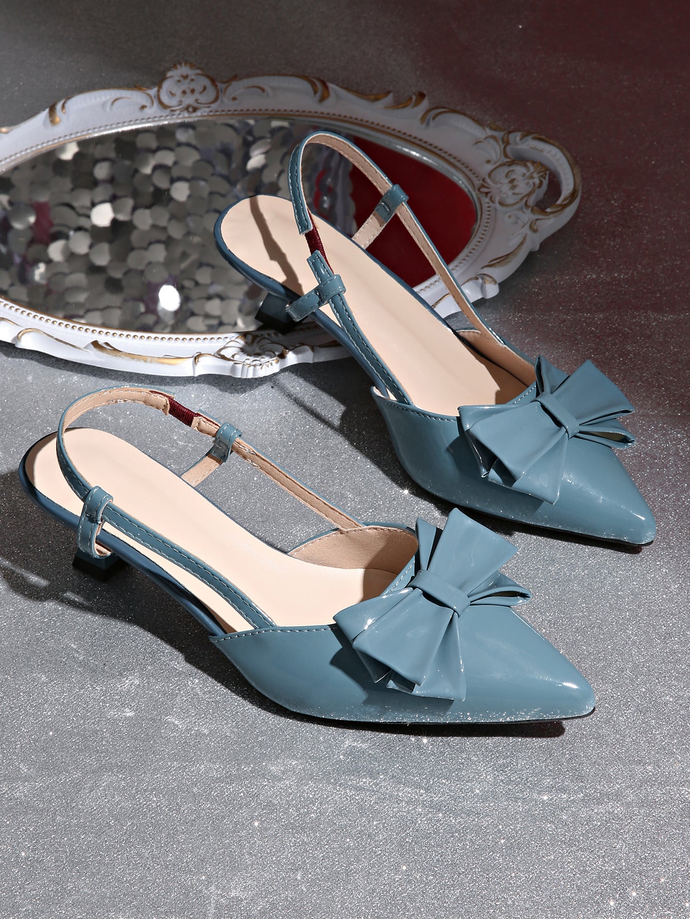 Mescini blue bow pointed toe slingback kitten heels, pair placed next to a carved mirror, US women's sizes