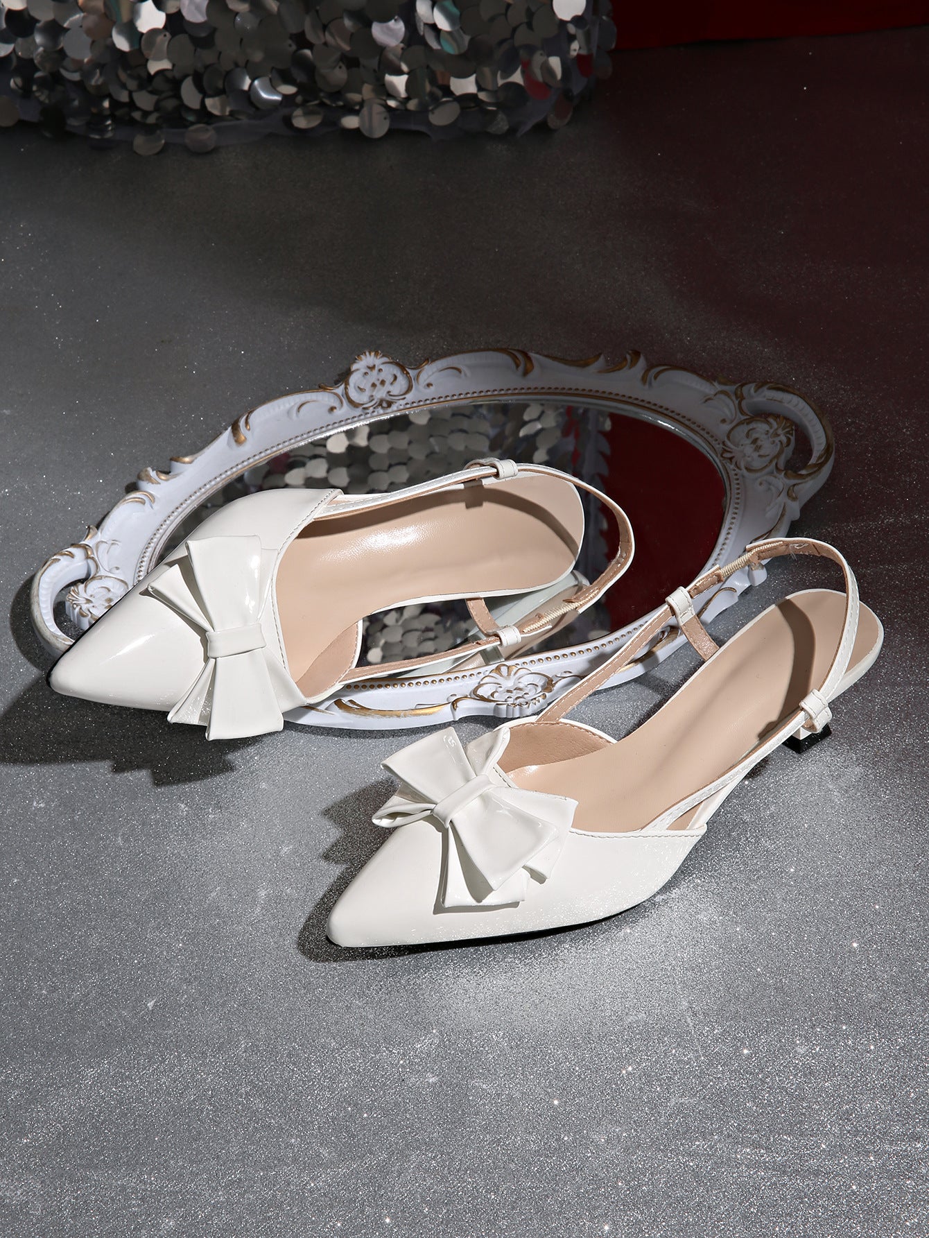 Mescini white bow pointed toe slingback kitten heels, pair resting beside an ornate mirror, US women's sizes