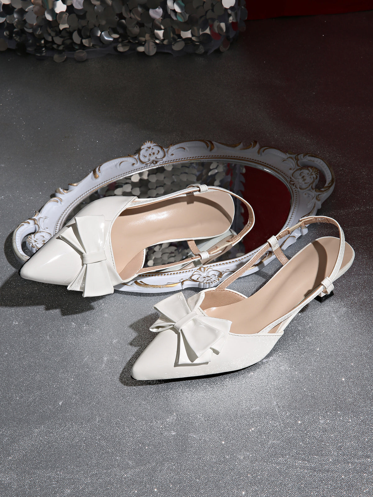 Mescini white bow pointed toe slingback kitten heels, pair resting beside an ornate mirror, US women's sizes