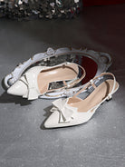 Mescini white bow pointed toe slingback kitten heels, pair resting beside an ornate mirror, US women's sizes