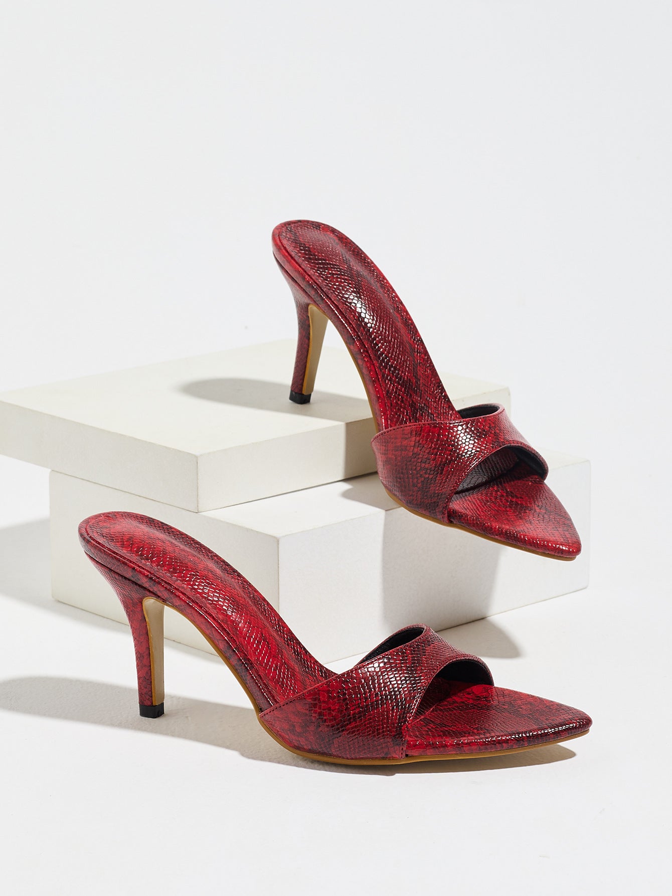 Mescini red snake print pointed toe mule heels, the pair displayed on white blocks, US women's sizes
