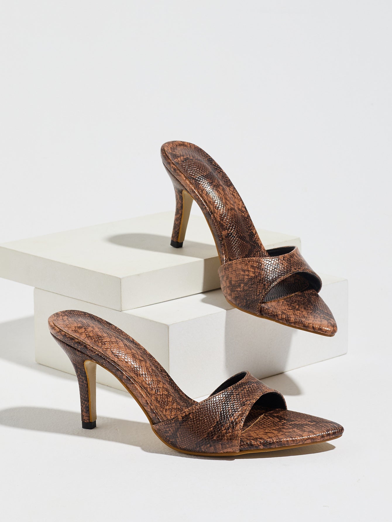 Mescini brown snake print pointed toe mule heels, the pair on white display blocks, US women's sizes