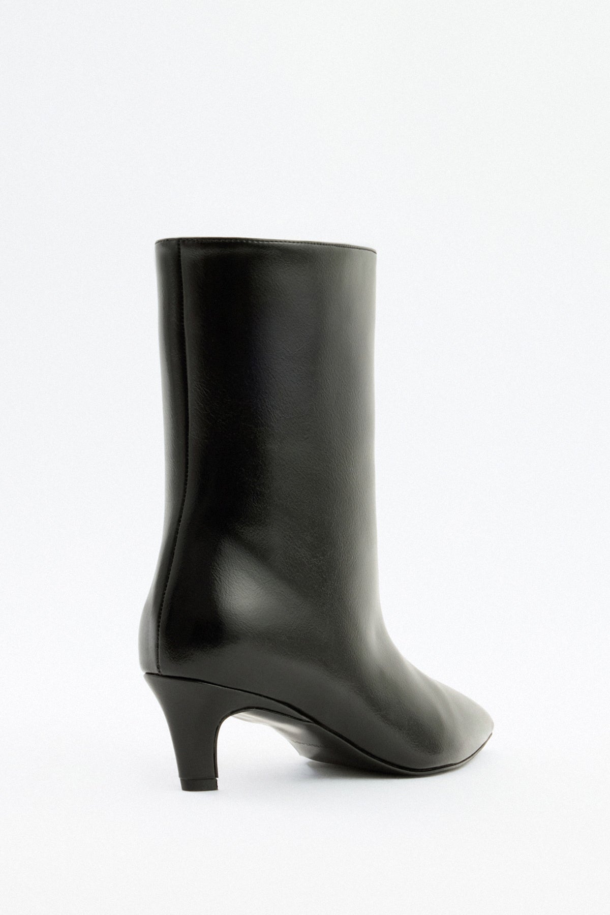 Mescini black pointed toe ankle boots, worn under a short white dress, US size guide