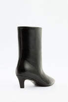Mescini black pointed toe ankle boots, worn under a short white dress, US size guide