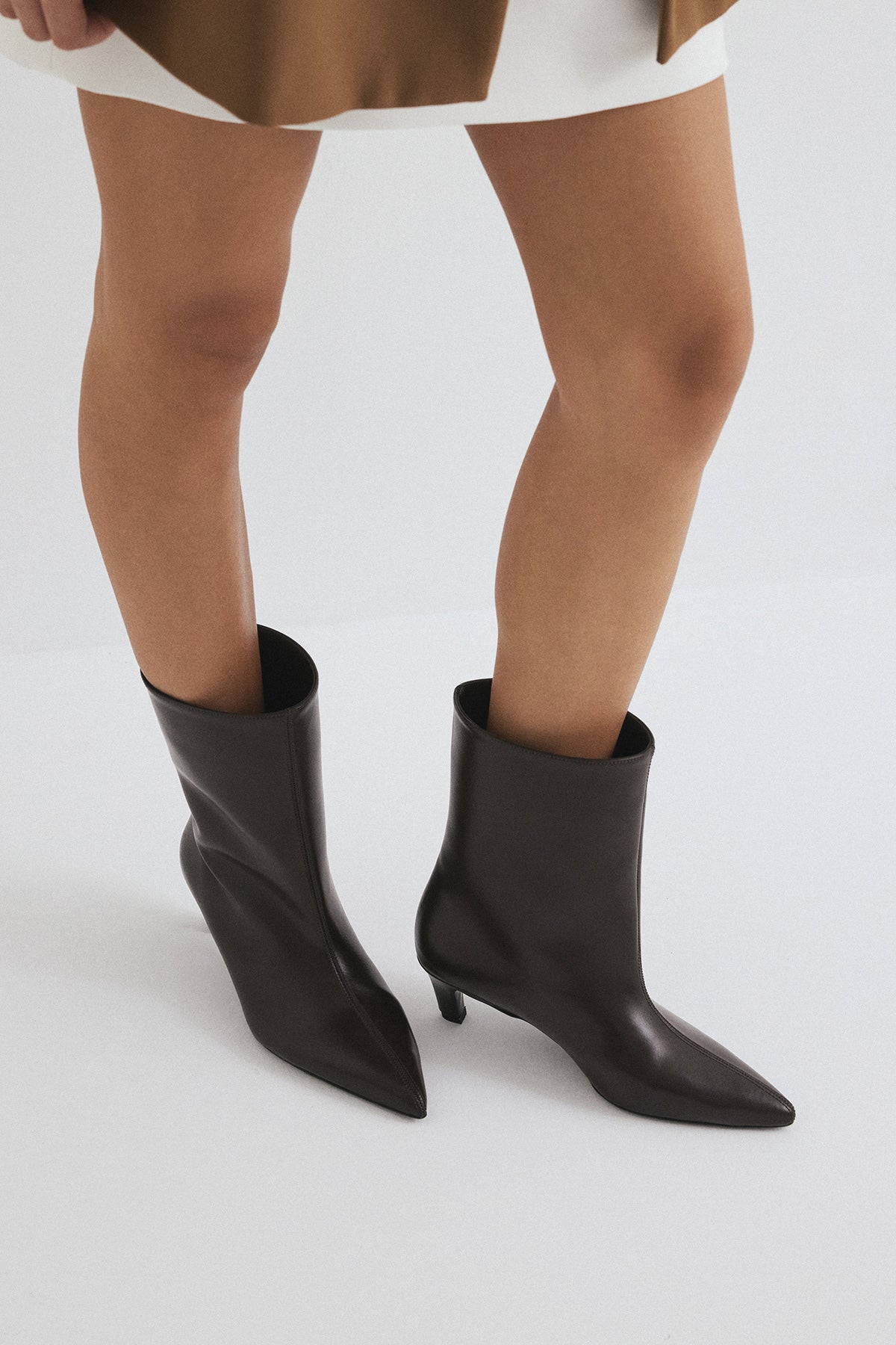 Mescini dark brown pointed toe ankle boots, worn under a short white dress, US sizes