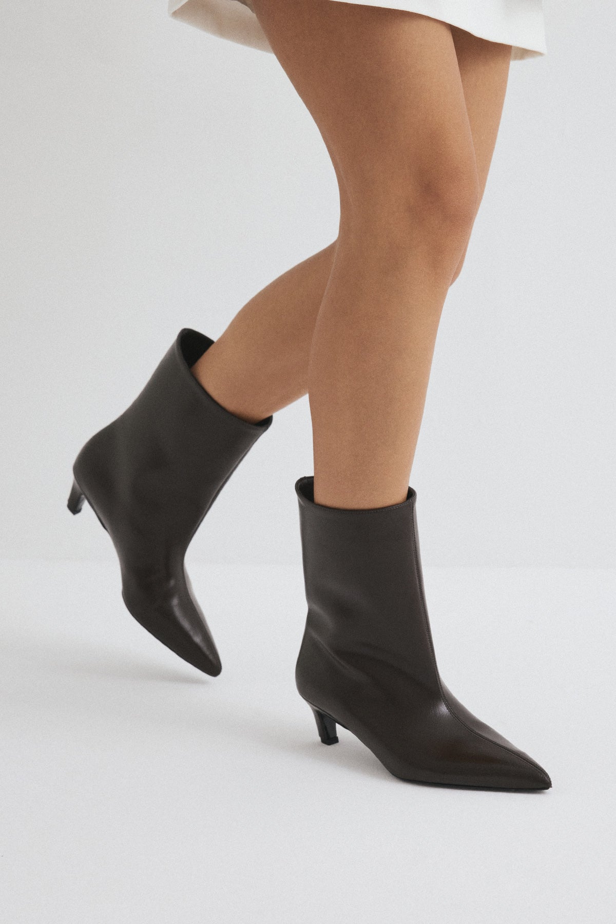 Mescini dark brown pointed toe ankle boots, worn mid stride, heel lifted, US sizes