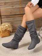 Mescini gray pleated slouch flat mid calf boots, worn by a model at a wooden wall, US women's sizes