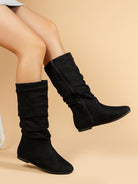 Mescini black pleated slouch flat mid calf boots, worn by a seated model, legs crossed, US women's sizes
