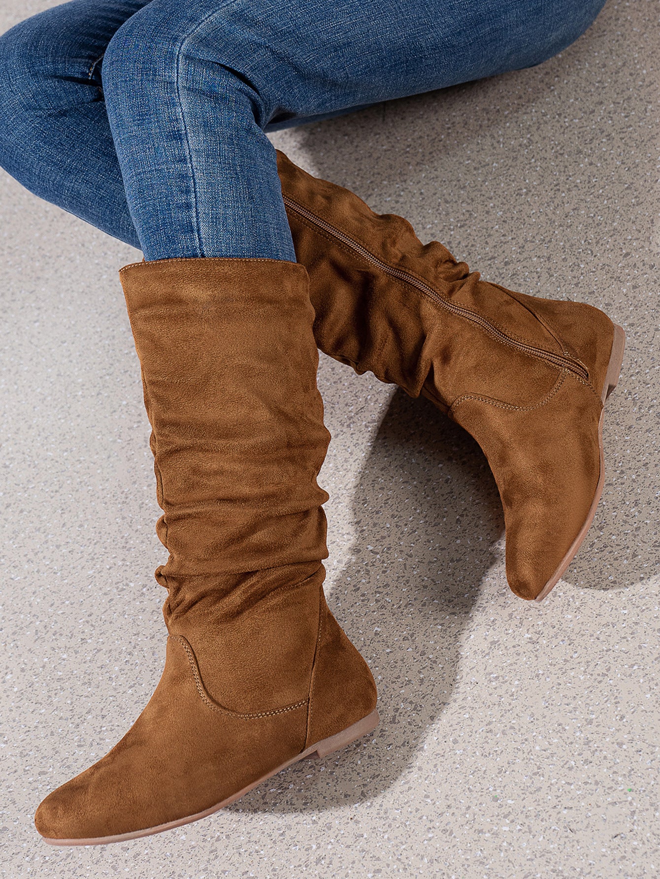 Mescini brown pleated slouch flat mid calf boots, worn with jeans by a seated model, US women's sizes
