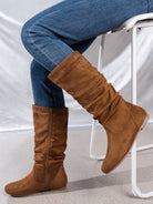 Mescini brown pleated slouch flat mid calf boots, worn with jeans beside a chair, US women's sizes