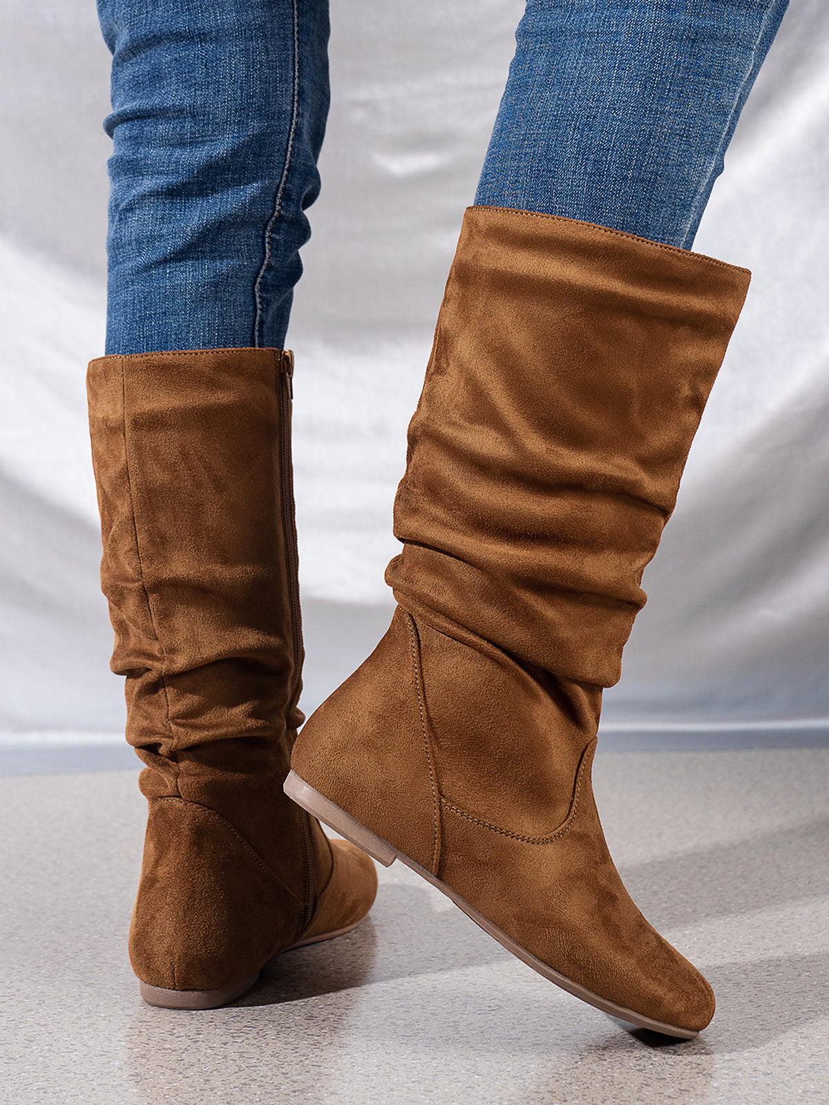 Mescini brown pleated slouch flat mid calf boots, worn with jeans, model standing, US women's sizes