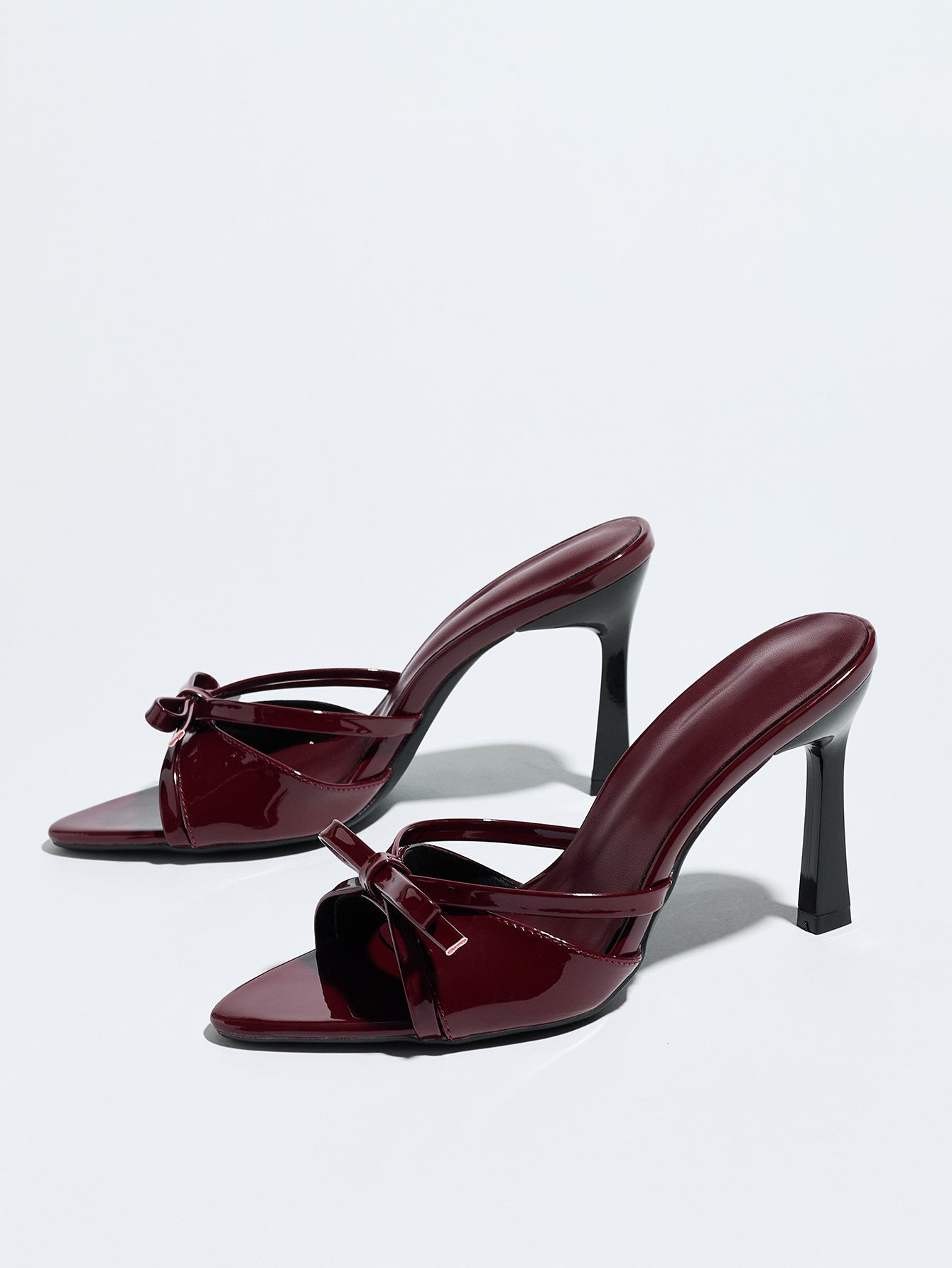 Mescini burgundy bow pointed toe stiletto mules, pair angled on a white backdrop, US women's sizes