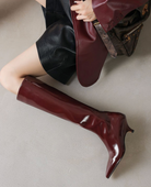 Mescini burgundy kitten heel knee high boots, worn by a seated model with a bag, US women's sizes