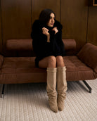 Mescini beige slouchy knee high boots, worn by a model seated on a bench, US sizes
