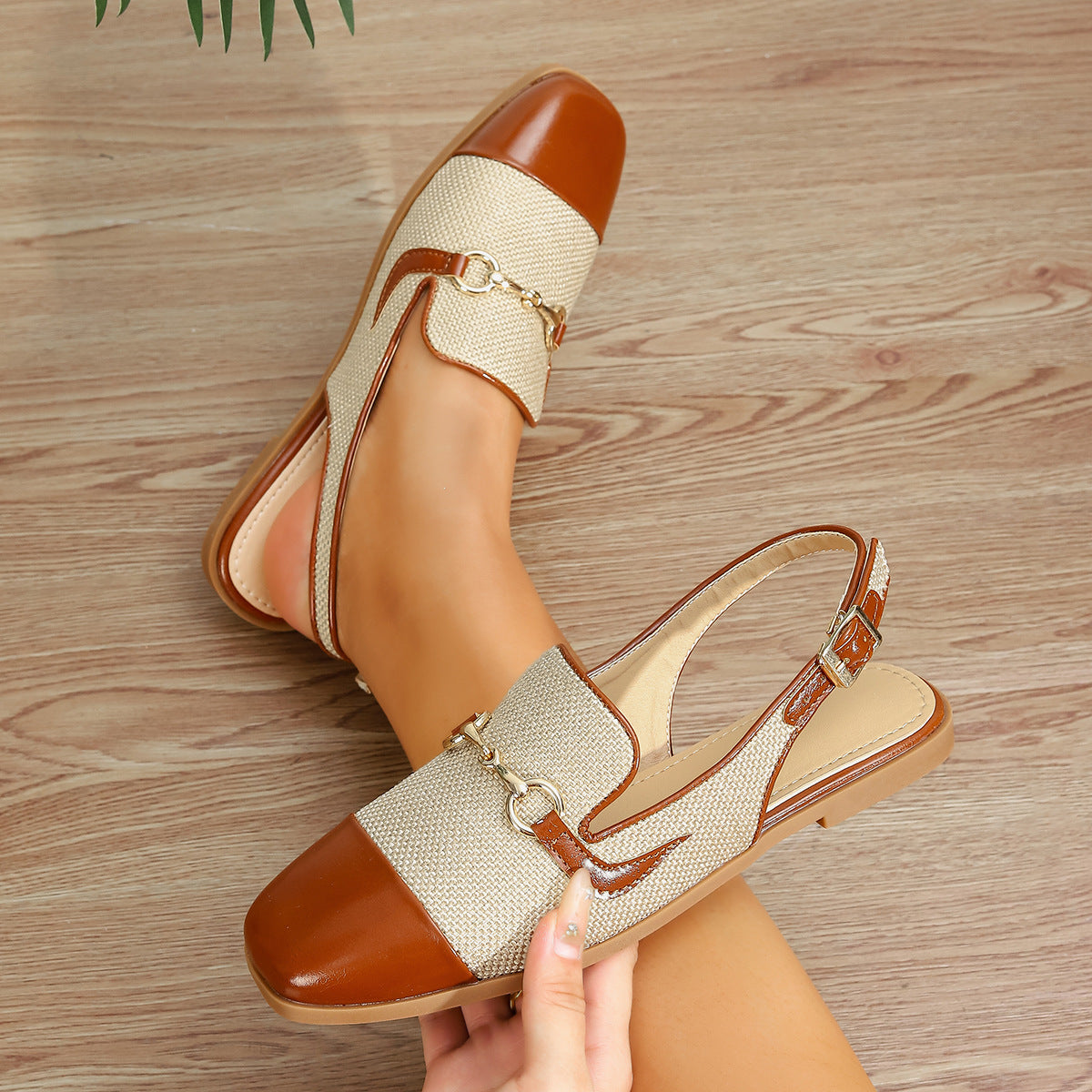Mescini brown cap toe slingback flat sandals, held in a hand, sling strap in view, US women's sizes