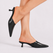 Mescini black pointed toe kitten heel mules worn on bare feet, model standing, US women's sizes