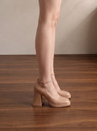 Mescini nude ankle strap platform block heel pumps, worn standing on a wooden floor, US women's sizes