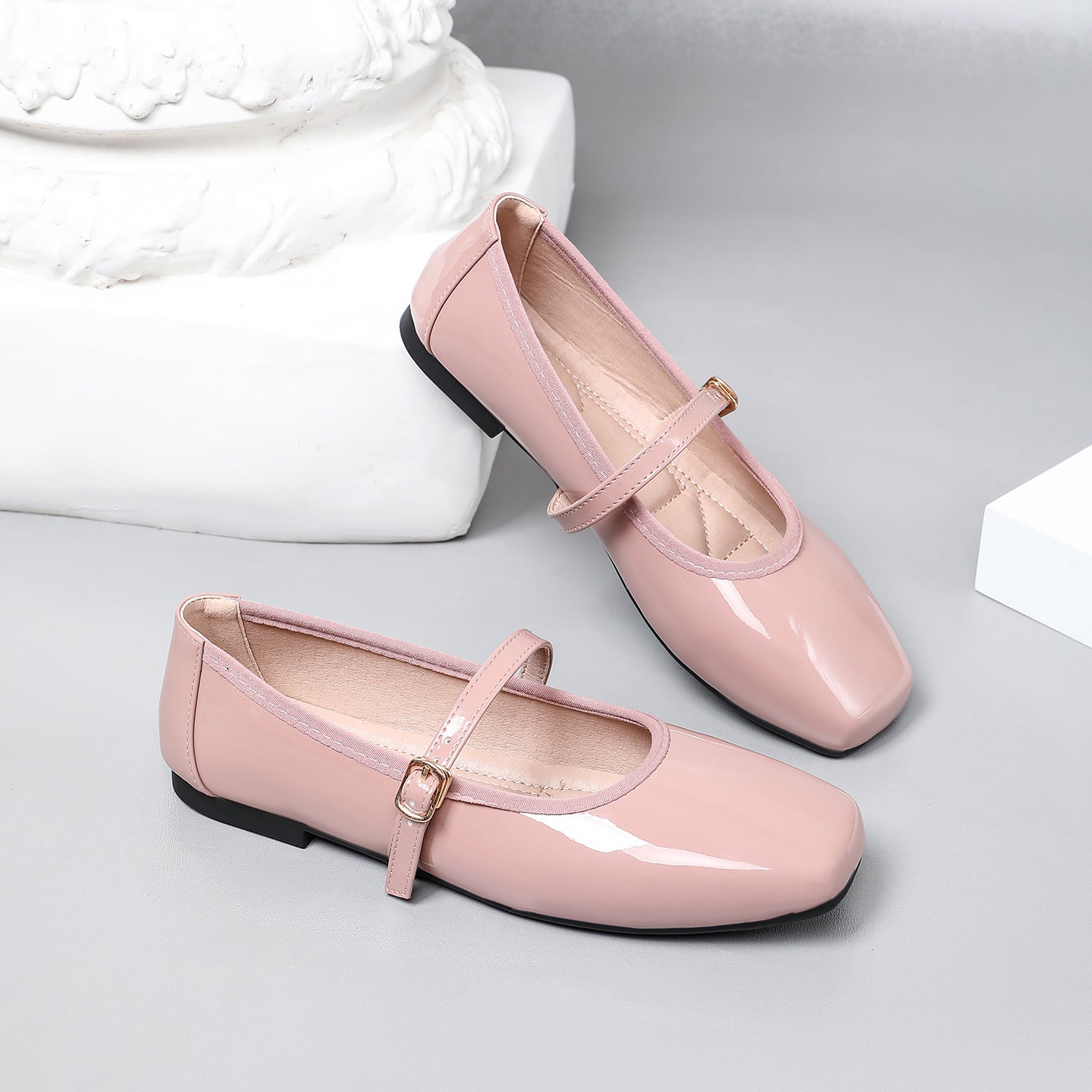 Mescini pink patent square toe mary jane flats, pair resting on a white plaster block, US women's sizes