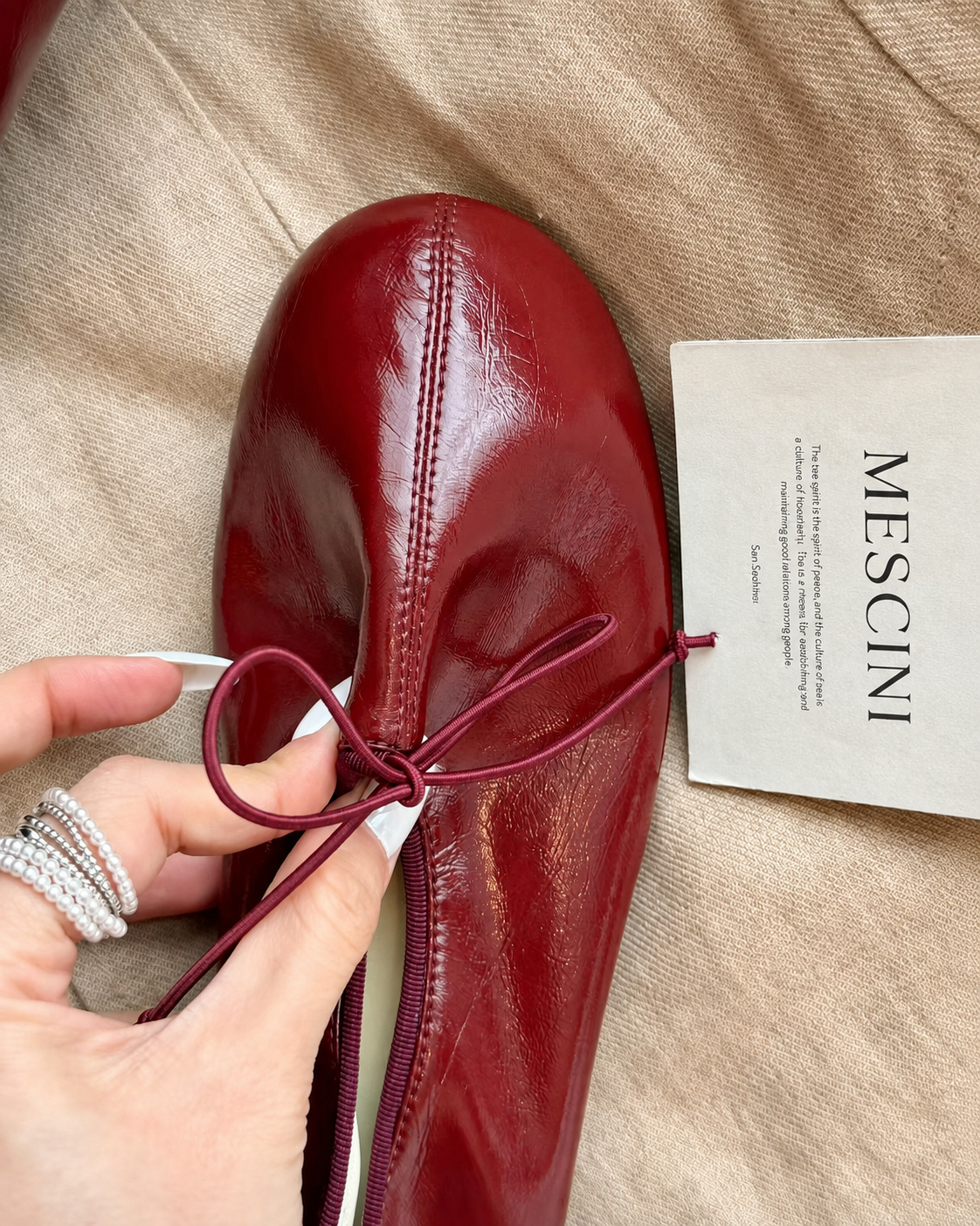 Mescini burgundy soft drawstring bow ballet flats, close up of one shoe held in a hand, US women's sizes