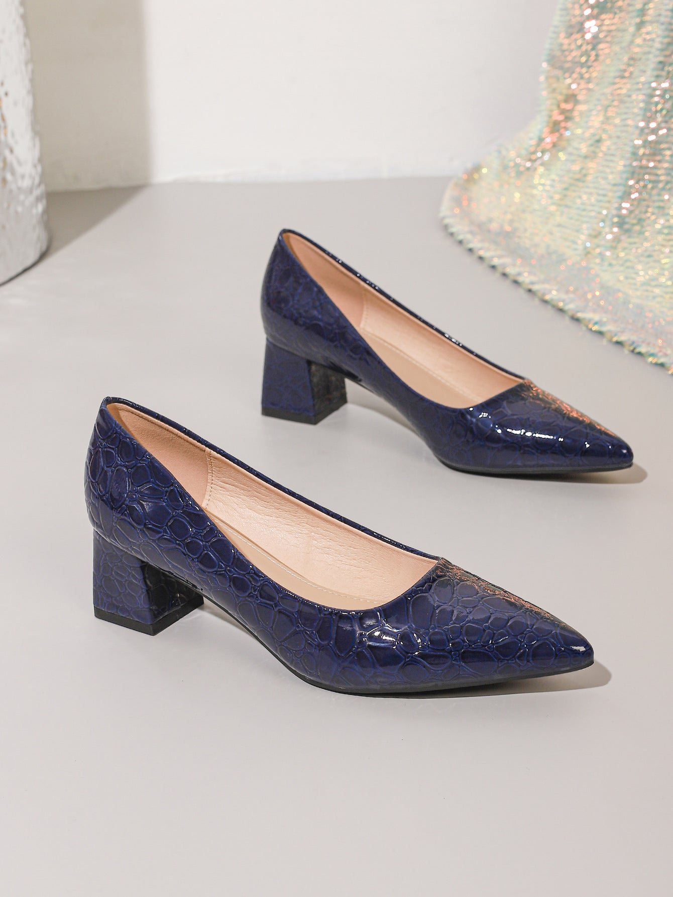 Mescini navy blue croc embossed block heel pumps, the pair set on a pale step, US women's sizes