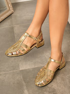 Mescini gold woven closed toe block heel sandals, worn on the model on a tiled floor, US women's sizes